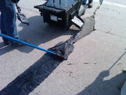 Beckage crew applying Crafco Mastic One on a pavement repair