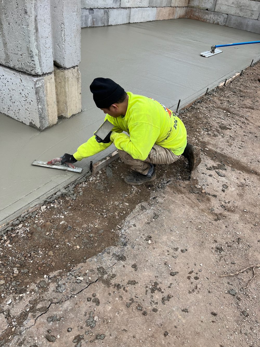 Beckage Sealcoating crew member hand-finishing the edge of a freshly poured concrete slab in New Jersey