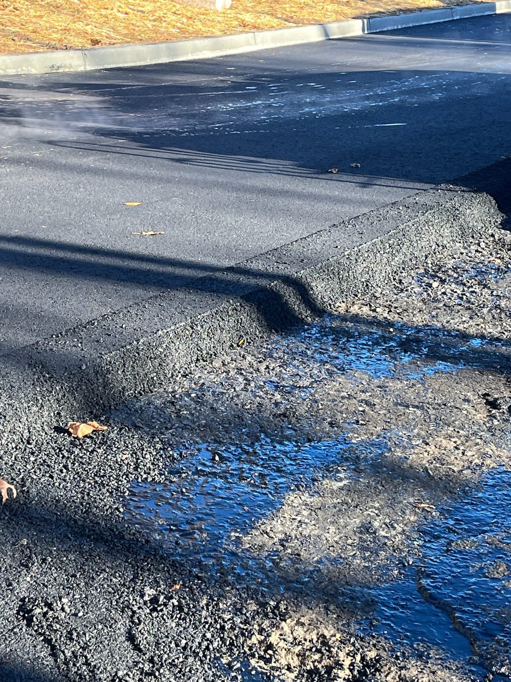Close-up of a freshly laid asphalt mat edge compacted against the base course on a NJ paving job