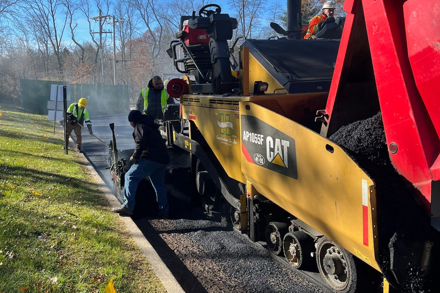 Beckage crew laying hot asphalt behind a Caterpillar paver on a commercial job in New Jersey